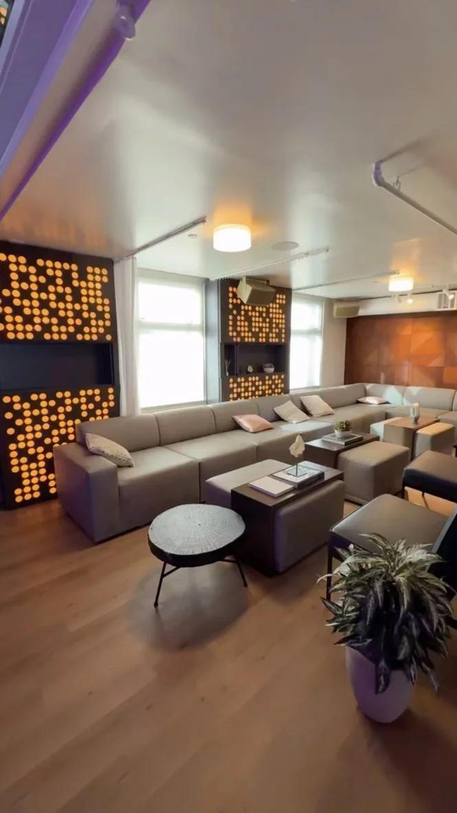 Lounge with beige modular sectionals and wall panels of amber LED dot-matrix lighting in dark wood frames