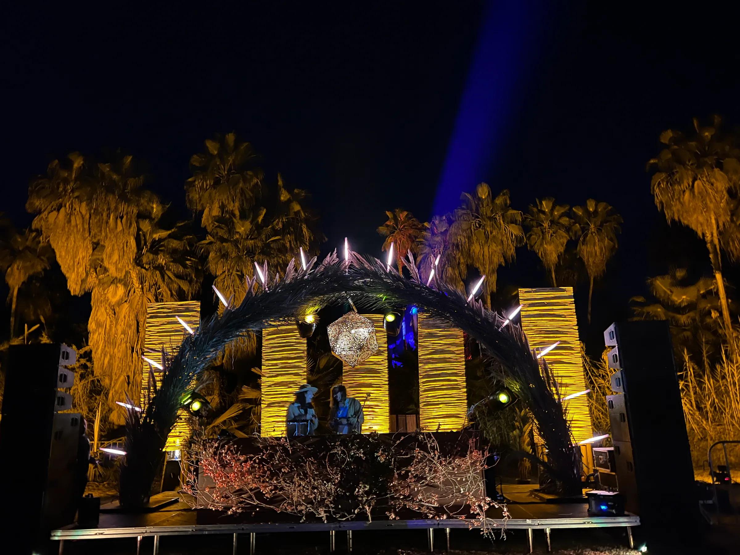Yellow slatted arch stage under blue beams at night